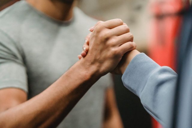 Two people clasp hands in show of support.