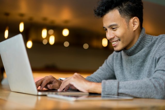 A young man smiles as he sees his options for online classes.