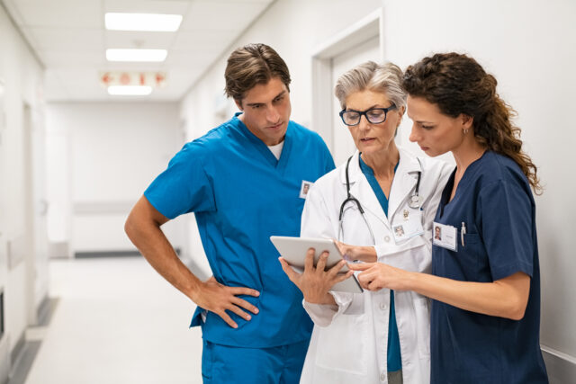 A doctor and nurses discuss a patient's chart