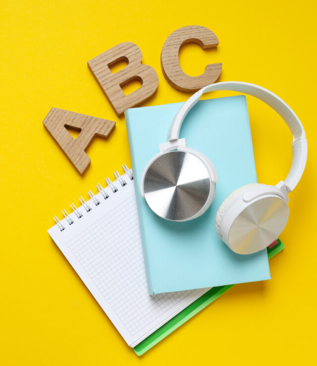The letters ABC sit next to a notebook and some headphones.