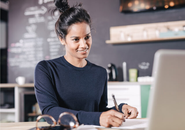 Young woman takes note as she learns online.