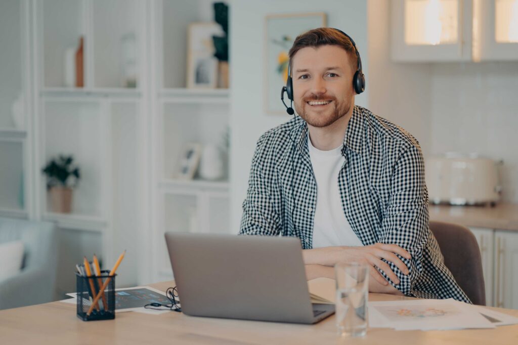 A tutor sitting in front of a laptop wearing a headset